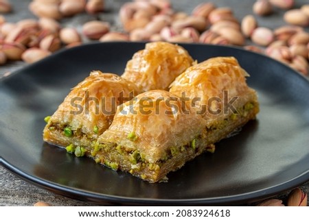 Pistachio baklava on a wooden background. Turkish style pistachio baklava presentation and service. Horizontal view. close up Royalty-Free Stock Photo #2083924618