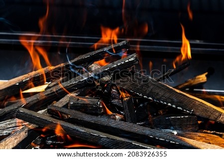 Barbecue grill pit with glowing and flaming hot open fire with red flame, hot charcoal briquettes and embers