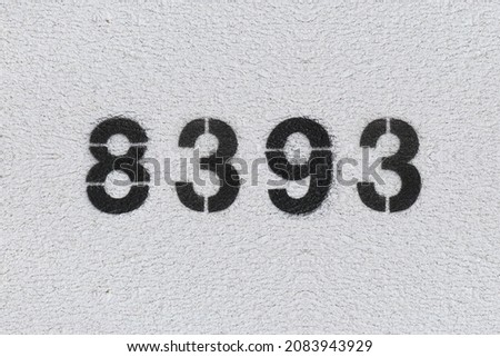 Black Number 8393 on the white wall. Spray paint. Number eight thousand three hundred ninety three.