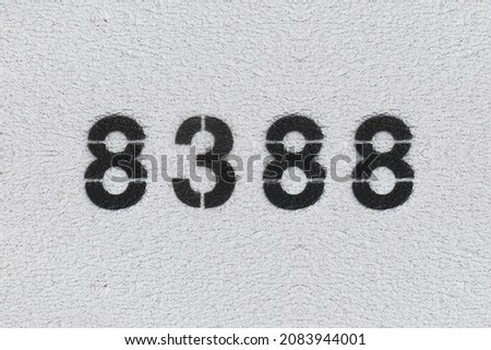 Black Number 8388 on the white wall. Spray paint. Number eight thousand three hundred and eighty.