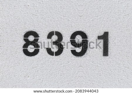 Black Number 8391 on the white wall. Spray paint. Number eight thousand three hundred and ninety one.