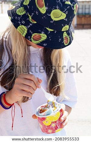 Teen girl eats fried ice cream on the beach