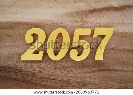 Golden Arabic numerals 2057 on a dark brown to white wood grain background.