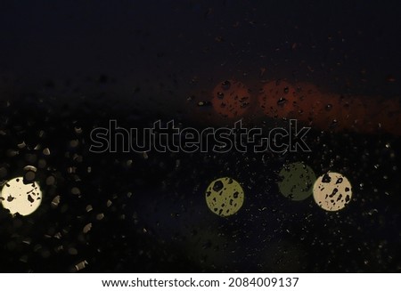 night window in raindrops with blurred lights on a dark background