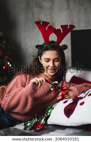 Girl with deer antlers on the background of the Christmas tree.