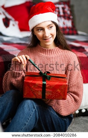 A girl in a Santa hat with gifts on the background of the New Year's interior.