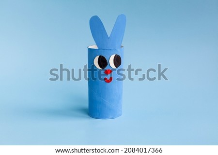 Holiday easy DIY craft idea for kids. Toilet paper roll tube toy cute rabbit on blue background. Creative New Year, Easter and xmas decoration eco-friendly, reuse, recycle handmade minimal concept