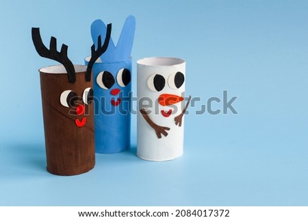 Holiday easy DIY craft idea for kids. Toilet paper roll tube toy rabbit, snowman, deer on blue background. Creative New Year and Christmas decoration eco-friendly, reuse, recycle handmade concept