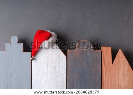 Christmas and New Year background as a symbol of the coming holiday. Silhouettes of houses carved from wood, Santa hat, copy space