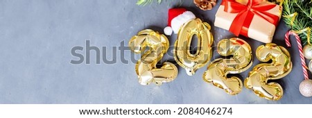 Happy new year 2022 background. Metallic balloons golden color on gray concrete background with copy space. Flat lay, top view, mockup, overhead. Winter holiday celebration