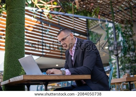 Young handsome businessman working on his laptop while sitting in a cafe