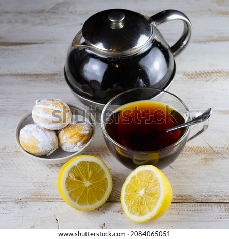 image of cookies, cups of tea, teapot with tea and lemon on a wooden table 