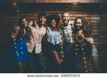 Group of friends having fun on the rooftop of a beautiful penthouse. Cinematic image of a group of people celebrating on the new year evening and night. Concept about holidays and lifestyle