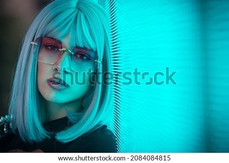 Image of a beautiful young woman posing against a led panel. teenager with alternative look and grey wig making urban portraits