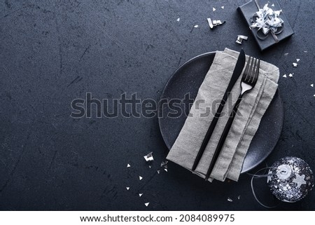 Christmas table setting black color with Christmas fir tree branches, Christmas silver balls and champagne, glasses on black background for xmas greetings. Merry Christmas and happy new year concept