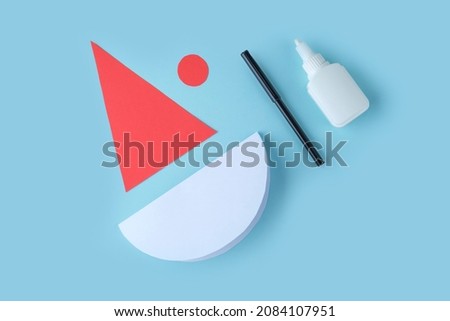 DIY and kid's creativity. Step by step instruction: how to make Santa claus from paper. Step2 cut out cap and circle for Santa's face from paper. Children's Christmas and New year craft