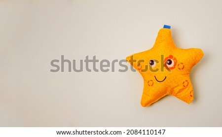 soft toy in the form of a yellow star on a gray background space for text, copy space