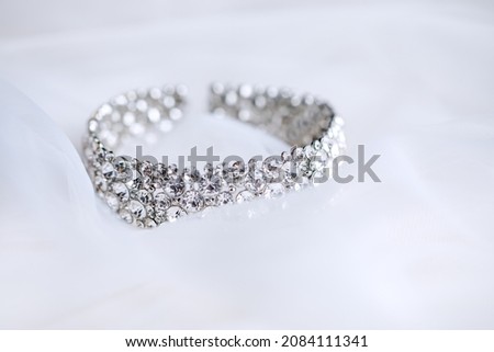 Bridal necklace with rhinestones close-up on a white organza. Wedding womens jewelry. Horizontal photo in light colors.