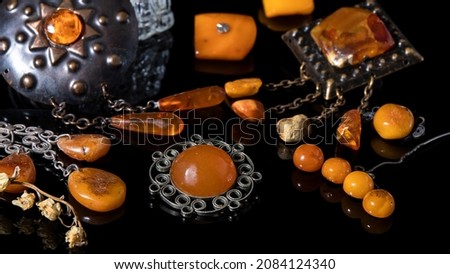 Isolated different orange Baltic amber brooches on a black background. Vintage amber jewelry with reflection. Royalty-Free Stock Photo #2084124340
