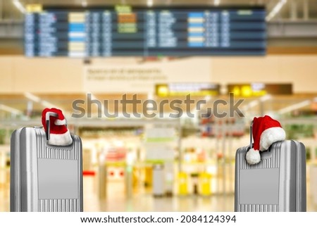 suitcases with christmas hats in airport building with unfocused terminal of departure in background