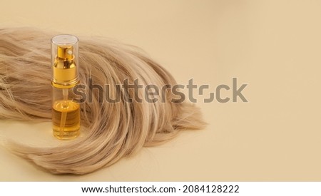 hair oil and blonde hair on a beige background in the form of a banner Royalty-Free Stock Photo #2084128222