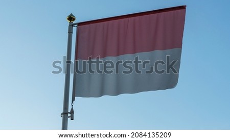 National flag of Monaco on a flagpole in front of blue sky with sun rays and lens flare. Diplomacy concept. International relations. Space for text.