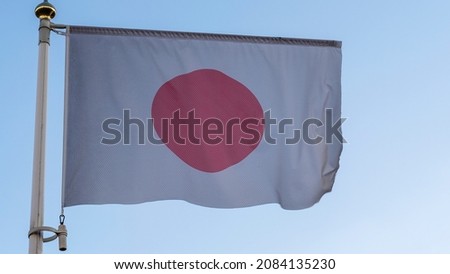 National flag of Japanese on a flagpole in front of blue sky with sun rays and lens flare. Diplomacy concept. International relations. Space for text.