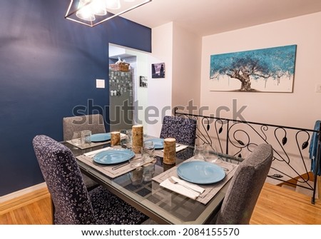 Luxury dinning room with glass table and stylish chairs. A table set for supper with art work in the background of a tree and photo of Siwash Rock in Stanley Park