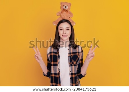 Photo of friendly funny positive lady teddy bear on head isolated yellow color background