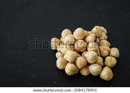 Ingredient for chocolates. A handful of hazelnuts. Hazel fruits. Appetizing picture. Roasted hazelnuts on a black background. A healthy snack.