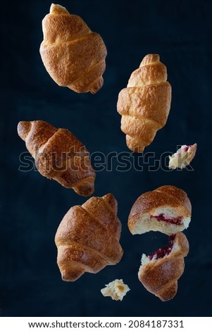Falling delicious fresh baked croissants on blue background