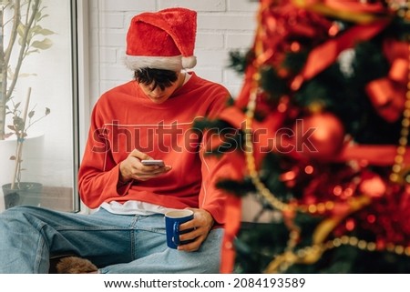 young man with mobile phone at home for christmas