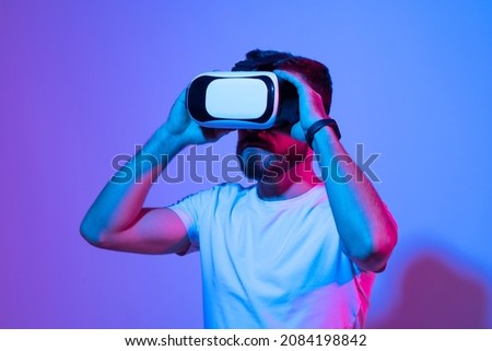 Closeup of young man wearing virtual reality goggles in modern studio. Smartphone using with VR headset.