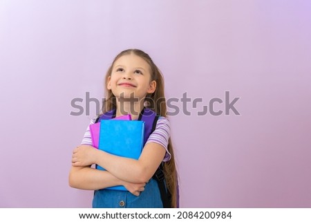 A schoolgirl with books in her hands looks up and smiles. Isolated background.