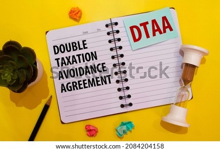 Closeup on businessman holding card with DTAA DOUBLE TAXATION AVOIDANCE AGREEMENT acronym text, business concept image with soft focus background and vintage tone