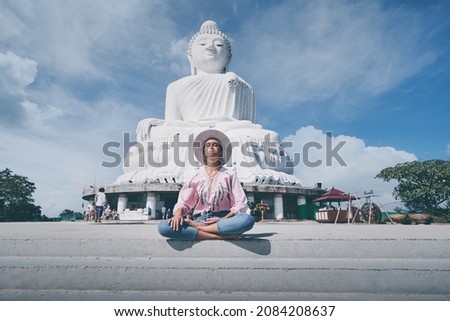 Traveling by Thailand. Pretty young woman sitting near the Big Buddha Temple, famous Phuket sightseeing.