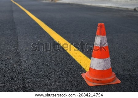 Traffic cone and temporary yellow line on to mark road works or temporary obstruction. Selective focus. Royalty-Free Stock Photo #2084214754