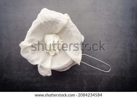 Making Labneh Cheese in a Cheesecloth Lined Strainer: Straining yogurt mixed with lemon juice and salt to make cheese Royalty-Free Stock Photo #2084234584