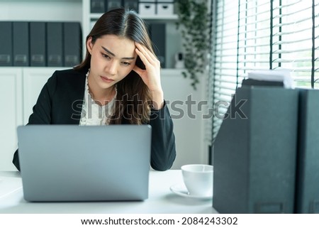 Asian beautiful businesswoman in formal wear use laptop work in office. Attractive professional female employee worker sit on table, feeling sick with headache while looking to many work in corporate.
