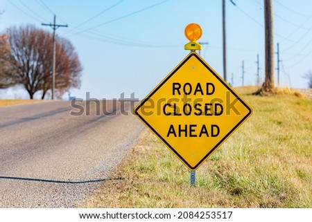 Yellow road closed ahead sign on rural road. Road construction, repair and travel safety concept.