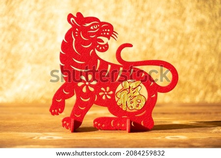 Chinese New Year of tiger 2022 mascot paper cut on a wood table in the morning the Chinese means fortune no logo no trademark Royalty-Free Stock Photo #2084259832