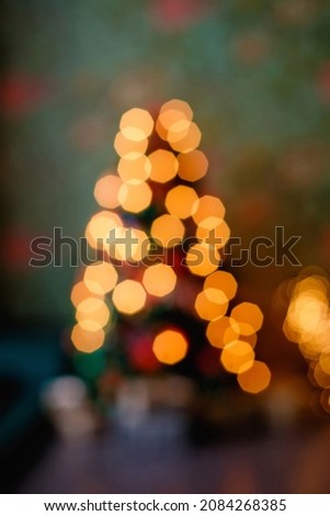Abstract Christmas tree with bokeh decorations blurred background. The Christmas tree in lights is out of focus. Vertical frame.