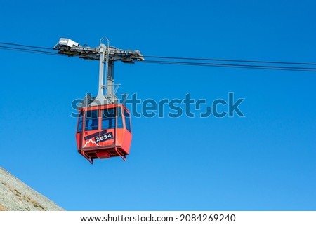 A red cable car on its way from Skalnate pleso to Lomnicky peak. Red gondola moving up to Lomnica peak in High Tatras Mountains. Slovakia. Royalty-Free Stock Photo #2084269240