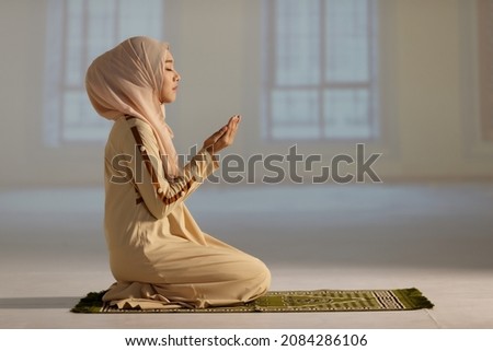 Beautiful Muslim woman in hijab dress sitting in mosque and praying. Royalty-Free Stock Photo #2084286106