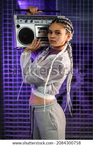 Young girl with white braids with a boombox on her shoulders, urban background, purple leds, 80s style, retro photography, vertical photo