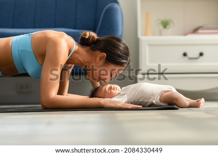 Side view of Wellness Asian woman mom doing plank exercise and kissing her baby at cozy home.Happy healthy mother yoga plank with newborn baby boy sleep and lying on yoga mat.Yoga Mom and Baby Concept Royalty-Free Stock Photo #2084330449