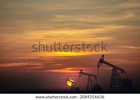 the evening silhouette of the pumping unit with Colorful dramatic sky in the countryside