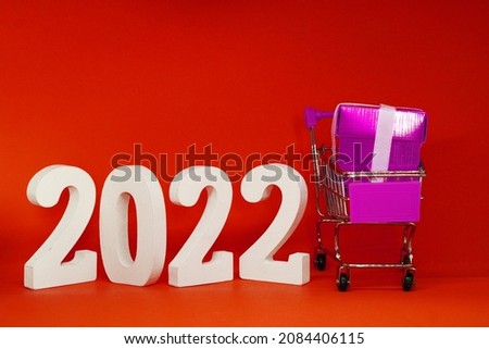 2022 number with pink Gift Box in shopping cart on red pattern background - End of year 2021 and Happy new year 2022 concept - Online Shopping Box , Marketing promotion advertise design - holiday