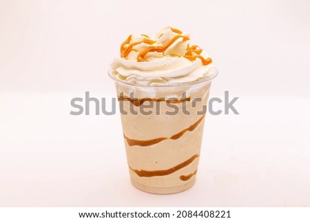 Caramel flavoured frappe served in a plastic cup with whipped cream and dressing.   Royalty-Free Stock Photo #2084408221