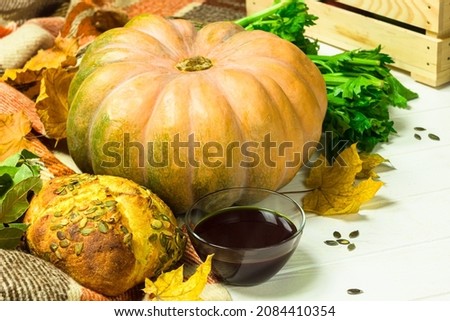 Yellow pumpkin, seeds, bread and oil in the bowl. Harvest on the table and fallen leaves. Fresh pumpking products
